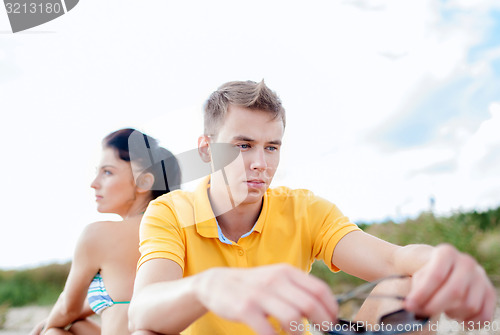 Image of unhappy couple sitting on beach