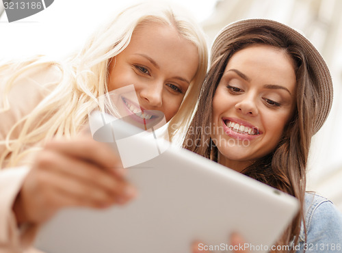 Image of two beautiful girls looking into tablet pc