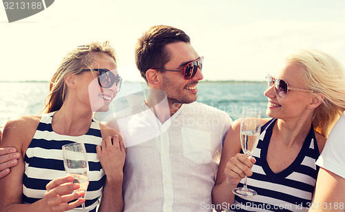 Image of smiling friends with glasses of champagne on yacht