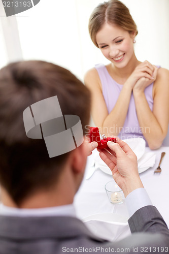 Image of excited young woman and boyfriend giving her ring