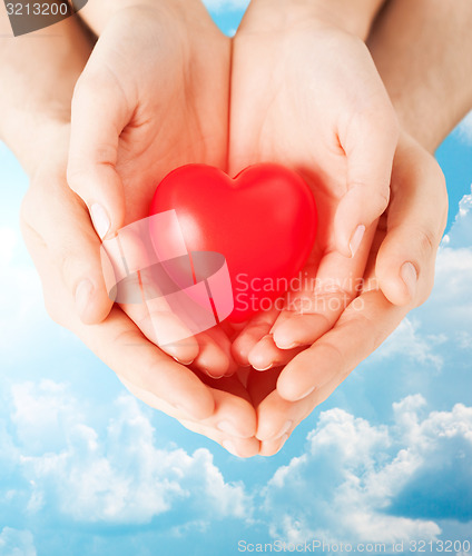 Image of close up of couple hands holding red heart