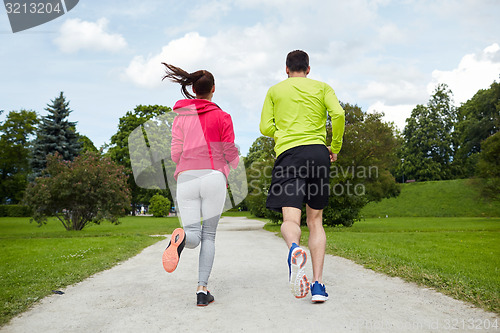 Image of smiling couple running outdoors