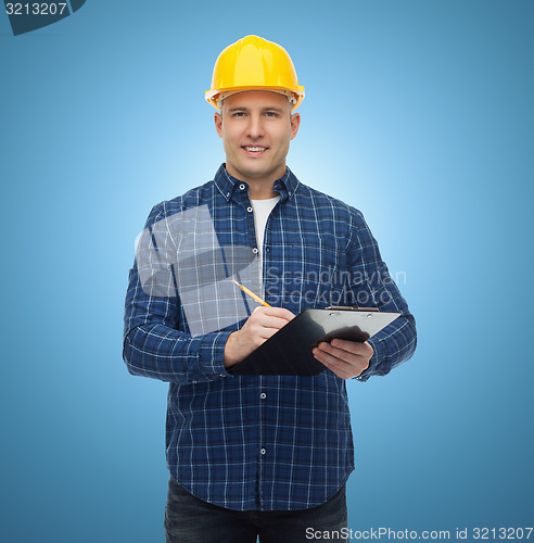 Image of smiling male builder in helmet with clipboard