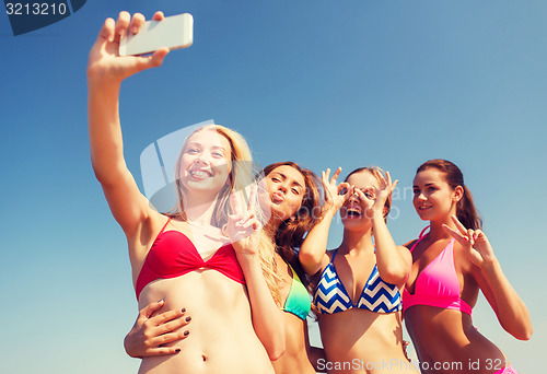 Image of group of smiling women making selfie on beach