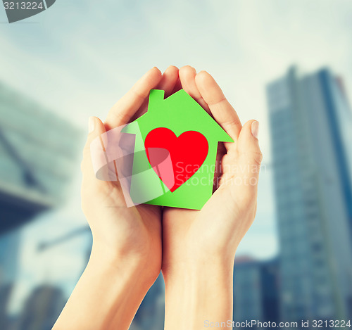 Image of hands holding green paper house