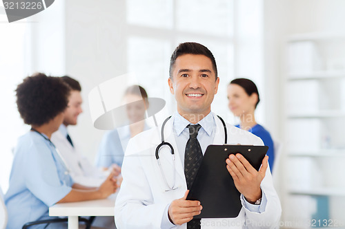 Image of happy doctor with clipboard over medical team