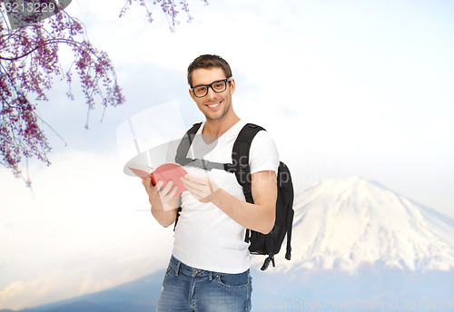 Image of happy young man with backpack and book travelling