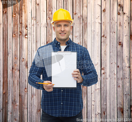 Image of smiling male builder in helmet with clipboard