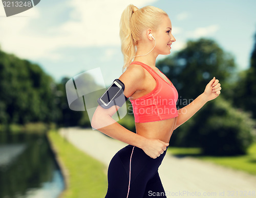 Image of sporty woman running with smartphone and earphones