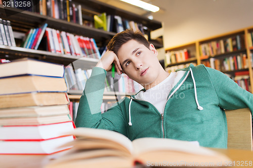 Image of bored student or young man with books in library