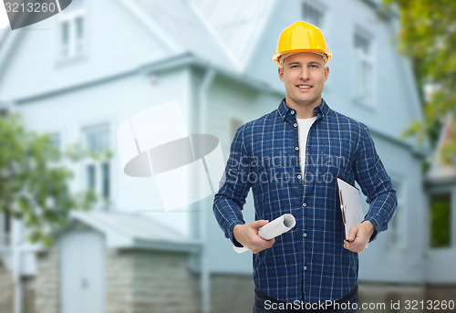 Image of smiling male builder in helmet with blueprint