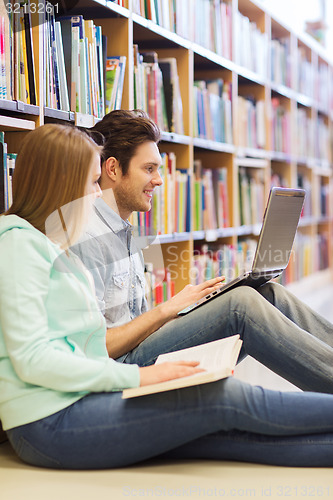 Image of happy students with laptop in library