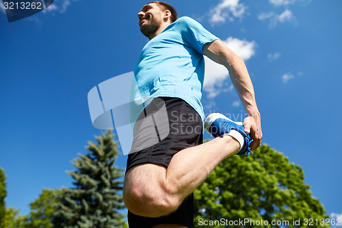 Image of smiling man stretching outdoors