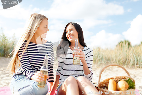 Image of happy young women drinking beer on beach