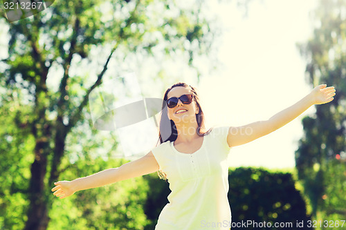 Image of smiling young woman with sunglasses in park
