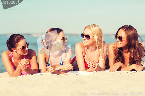 Image of group of smiling women in sunglasses on beach