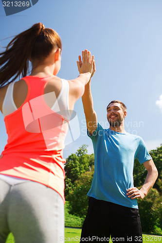 Image of two smiling people making high five outdoors