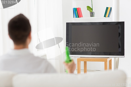 Image of man watching tv and drinking beer at home