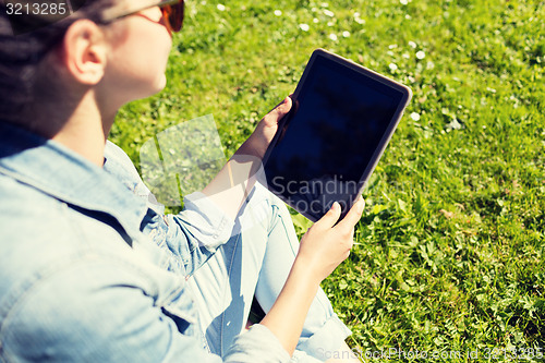 Image of close up of girl with tablet pc sitting on grass