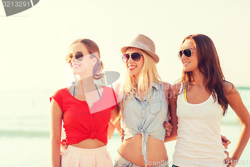 Image of group of smiling women in sunglasses on beach