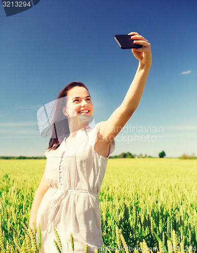 Image of smiling girl with smartphone on cereal field