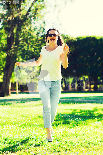 Image of smiling young woman with sunglasses in park