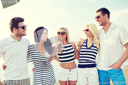 Image of smiling friends in sunglasses talking on beach