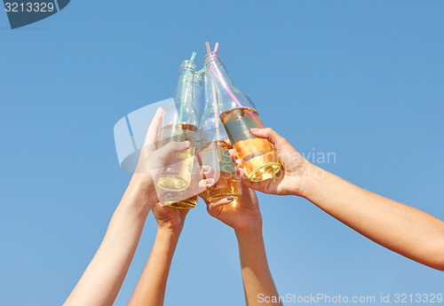 Image of close up of many hands clinking bottles