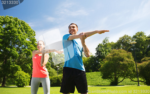 Image of smiling couple stretching outdoors