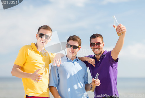 Image of happy friends with beer bottles on beach