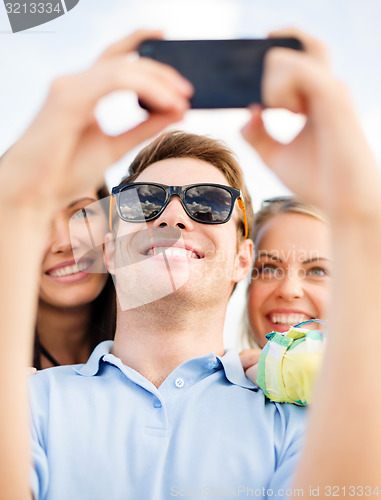 Image of group of friends taking selfie with cell phone