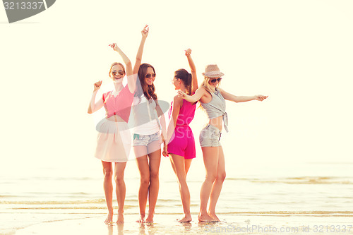 Image of group of smiling women dancing on beach