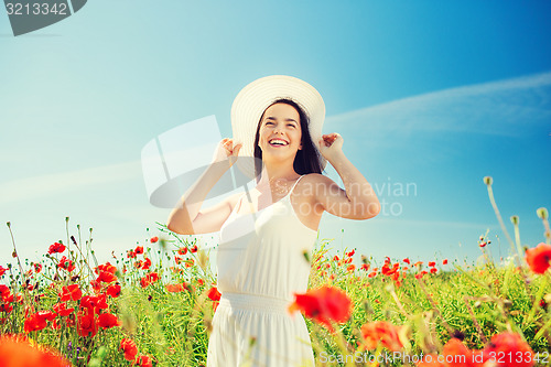 Image of smiling young woman in straw hat on poppy field