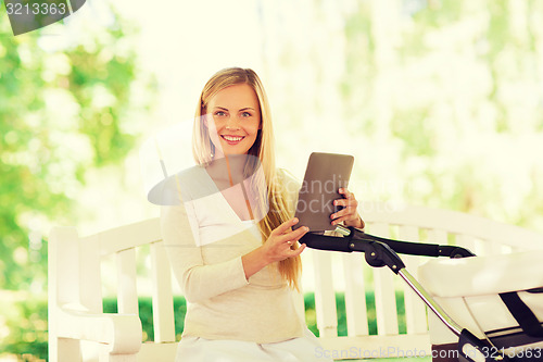 Image of happy mother with tablet pc and stroller in park