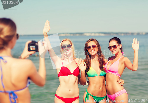 Image of group of smiling women photographing on beach