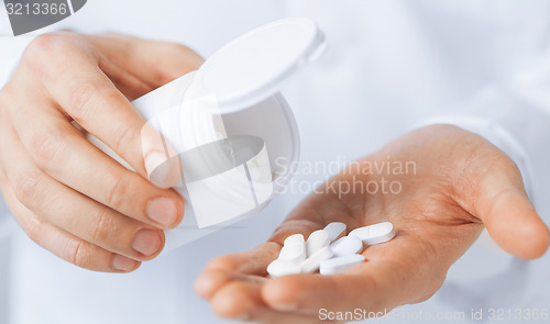 Image of doctor hands holding white pack and pills