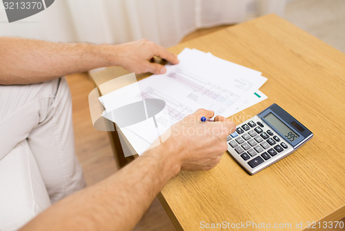 Image of close up of man with papers and calculator at home