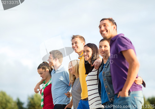 Image of group of happy friends walking along beach