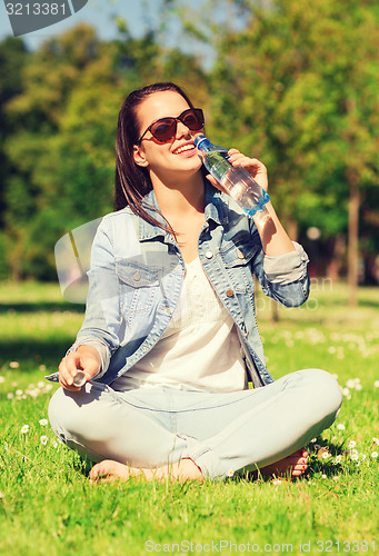 Image of smiling young girl with bottle of water in park