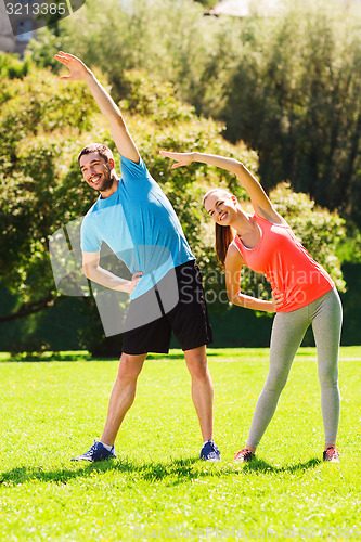 Image of smiling couple stretching outdoors
