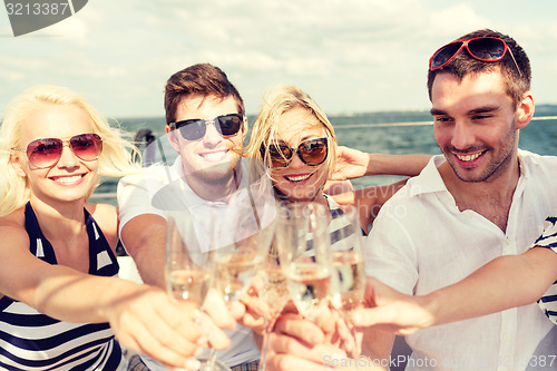 Image of smiling friends with glasses of champagne on yacht