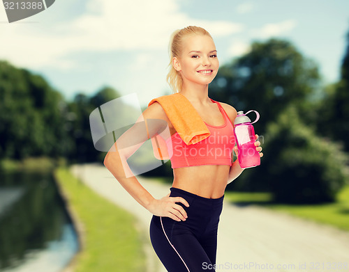 Image of smiling sporty woman with water bottle and towel