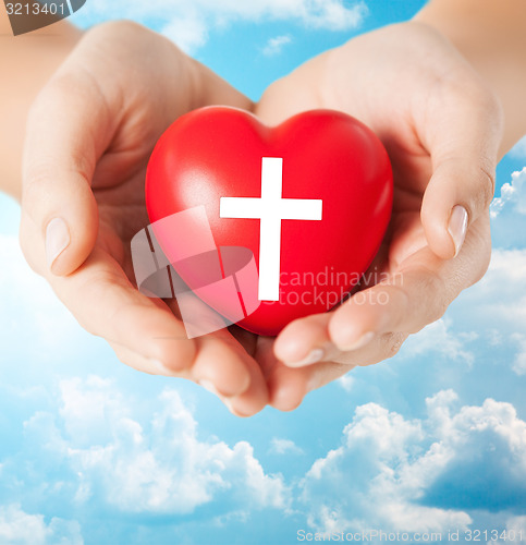 Image of close up of hands holding heart with cross symbol