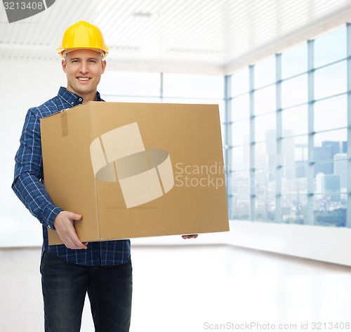 Image of smiling male builder in helmet with cardboard box