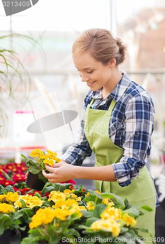 Image of happy woman holding flowers in greenhouse