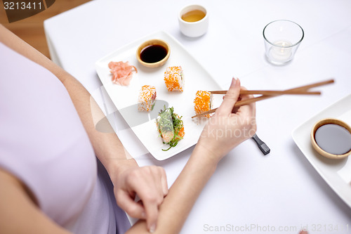 Image of close up of woman eating sushi at restaurant