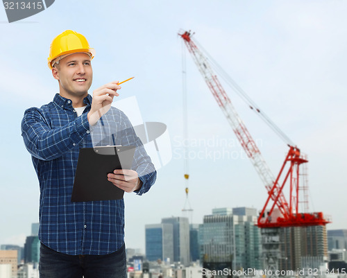 Image of smiling male builder in helmet with clipboard