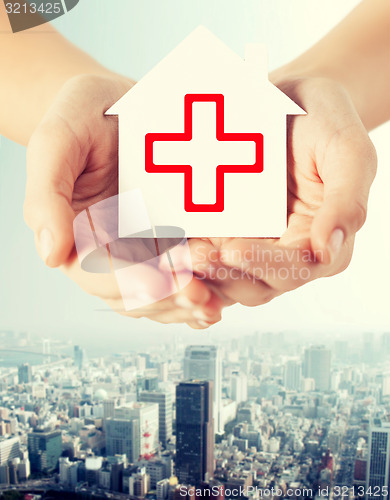 Image of hands holding paper house with red cross