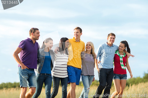 Image of group of happy friends walking along beach