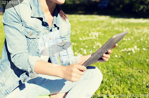 Image of close up of girl with tablet pc sitting on grass